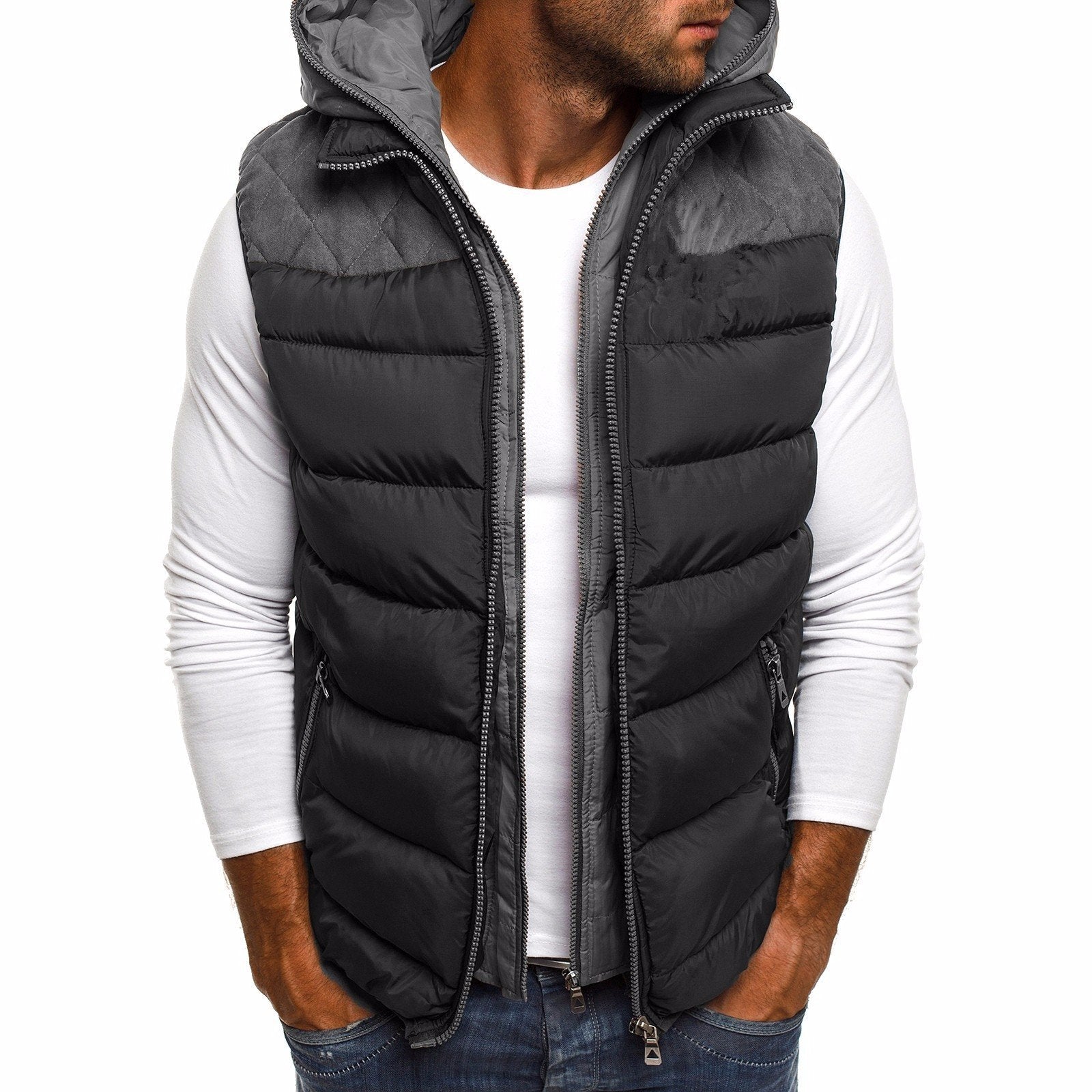 Un homme portant un gilet sans manches noir avec une capuche grise, sur un t-shirt blanc. Il adopte une posture décontractée, les mains dans les poches, mettant en valeur le design moderne et pratique de la veste idéale pour les journées fraîches d'hiver.