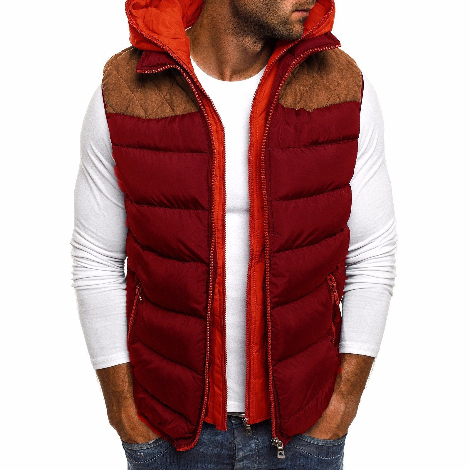 Homme portant un gilet sans manches rouge avec une capuche orange, sur un t-shirt blanc. Il adopte une posture décontractée, les mains dans les poches, avec un léger sourire. Le gilet a une partie supérieure en tissu marron contrastant, parfait pour l'hiver.