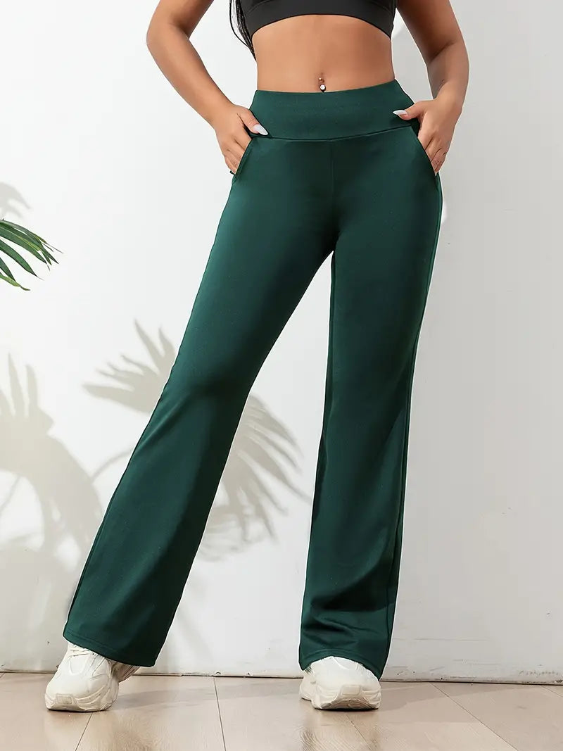 Femme portant un pantalon de yoga vert avec une taille haute et des poches latérales, associé à un crop top noir et des baskets blanches, en posture décontractée.