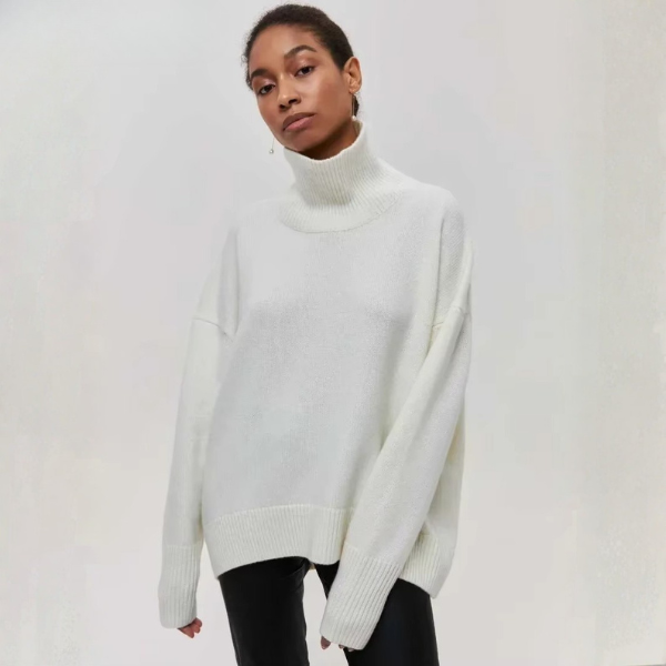 Femme portant un pull à col roulé épais de couleur blanche, au style ample et confortable. Le vêtement est parfait pour l’hiver, avec des manches longues et une texture douce qui offre chaleur et élégance décontractée.