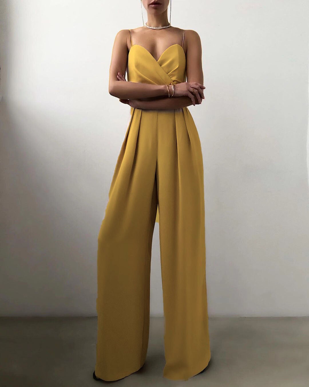 Combinaison sans manches de couleur jaune, avec un décolleté croisé et un pantalon large, offrant un look moderne et élégant.