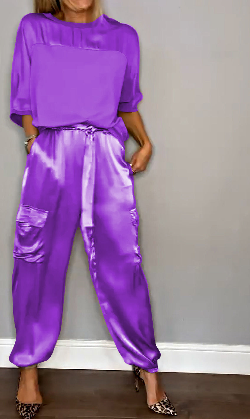 Une tenue élégante composée d'un haut satiné violet et d'un pantalon fluide avec des poches, porté avec des escarpins à motif léopard.