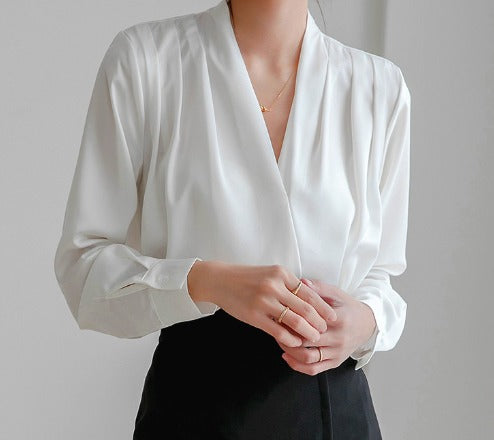 Blouse chic à manches bouffantes et décolleté en V, portée par une femme avec un pantalon noir, mettant en valeur un look élégant et raffiné.