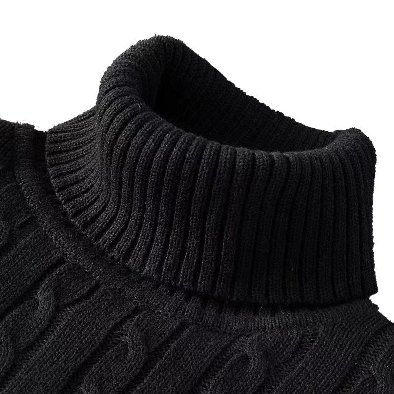 Zoom sur le col roulé d'un pull noir en maille côtelée à motif torsadé.