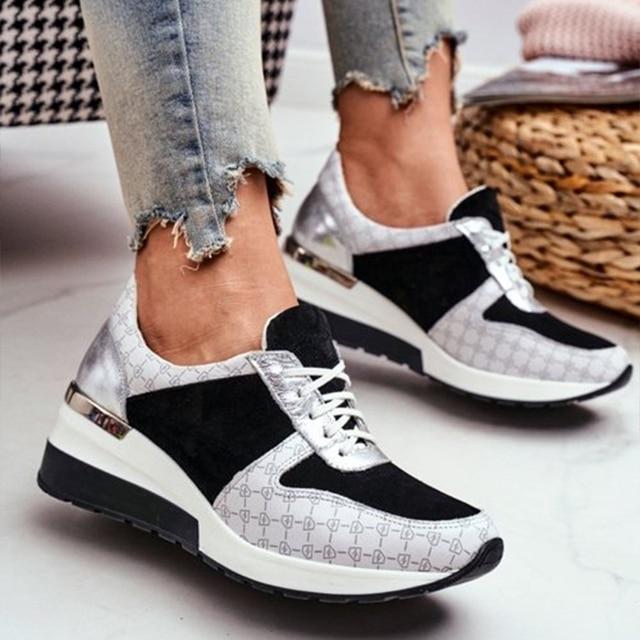 Paire de baskets pour femme au design moderne, combinant des matériaux argentés, noirs et gris texturés. Les chaussures présentent une semelle compensée blanche et noire, offrant confort et élégance. Le modèle est porté avec un jean effiloché, créant un style décontracté et chic, idéal pour un usage quotidien ou une tenue urbaine tendance.