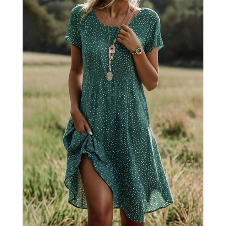 Robe d'été Adélina pour femme, moderne et légère. Ce modèle vert à imprimé pois blancs présente une coupe fluide et confortable, avec une fente élégante sur le côté. Parfaite pour les journées estivales, cette robe est idéale pour un look décontracté mais stylé, à porter avec des accessoires simples pour un effet chic.