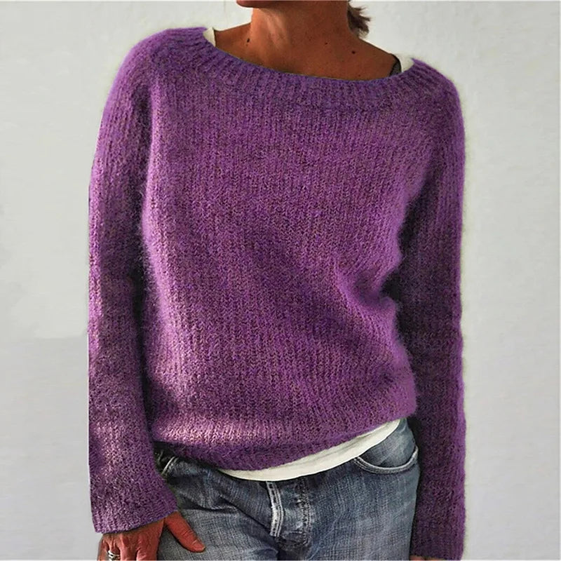 Femme portant un pull en maille violet à manches longues, doté d’une coupe décontractée et d’une encolure large, associé à un t-shirt clair et un jean, photographiée devant un fond neutre.