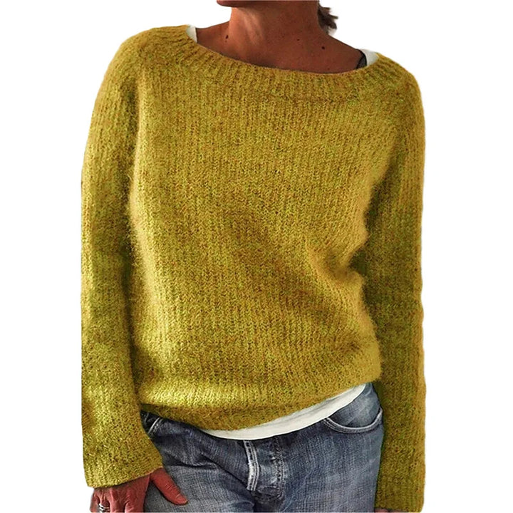 Femme portant un pull jaune moutarde en maille douce à manches longues, doté d’une coupe décontractée et d’une encolure large, superposé à un t-shirt clair et assorti à un jean, photographiée sur un fond neutre.
