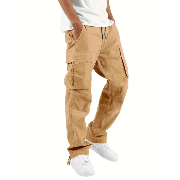 Pantalon cargo pour homme Adrienn, moderne et décontracté, de couleur beige. Ce modèle pratique avec des poches latérales et un cordon de serrage à la taille est idéal pour un look urbain et fonctionnel, parfait pour le quotidien.