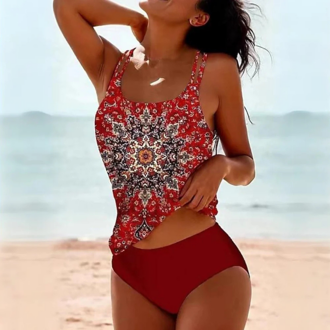 Maillot de bain Alizée pour femme, moderne et coloré. Ce modèle à imprimé mandala dans des tons rouges et oranges avec un bas assorti offre un look estival chic. Ses bretelles fines et sa coupe flatteuse assurent confort et style pour vos journées à la plage ou à la piscine.