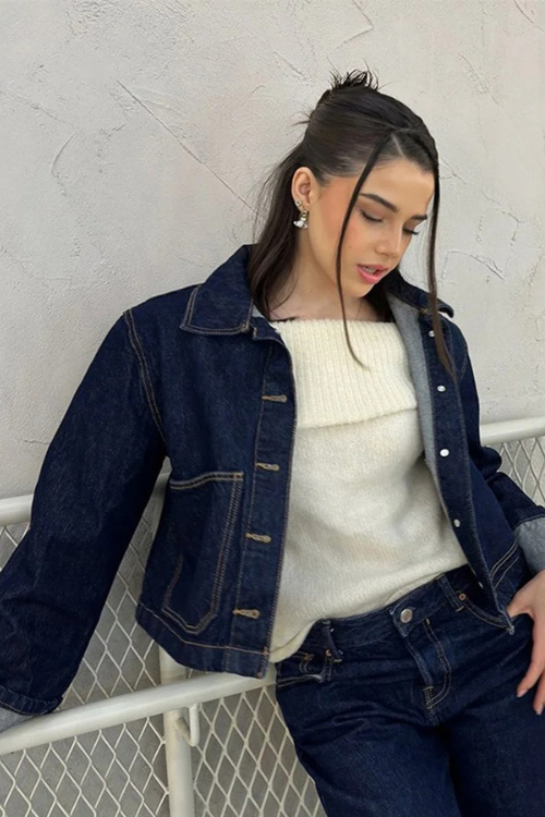 Ensemble femme moderne avec une veste en jean courte, stylée et confortable. La veste à boutons métalliques, associée à un pull doux et un jean assorti, présente un look chic et décontracté. Idéale pour un style urbain et tendance, cet ensemble met en valeur une silhouette féminine tout en offrant confort et élégance.