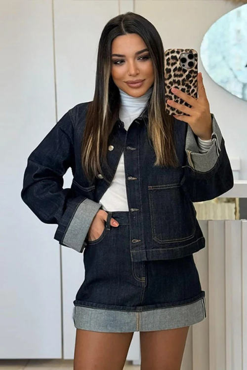 Ensemble femme moderne composé d'une veste en jean courte et d'une jupe assortie. La veste à boutons métalliques et les détails en denim clair sur les manches et l'ourlet de la jupe ajoutent une touche tendance. Ce look décontracté mais élégant est parfait pour un style urbain, offrant à la fois confort et modernité.