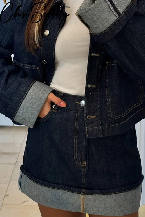 Zoom sur les détails de l'ensemble femme Ambrosia, composé d'une veste en jean courte et d'une jupe assortie. La veste présente des manches avec des bords en denim clair, et la jupe est également finie avec un ourlet clair pour un look cohérent et moderne. Les boutons métalliques ajoutent une touche chic à cette tenue décontractée, parfaite pour un style urbain élégant.