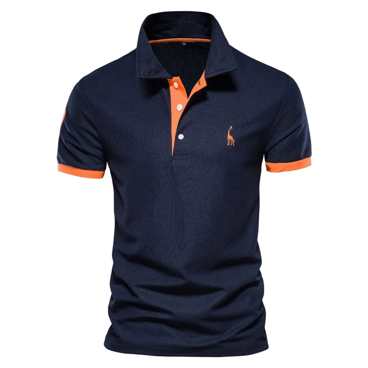 Polo pour homme de couleur bleu marine avec manches courtes, coupe ajustée, col classique à patte de boutonnage, détails contrastés orange au col et aux manches, petit logo brodé sur la poitrine, présenté sur fond blanc.