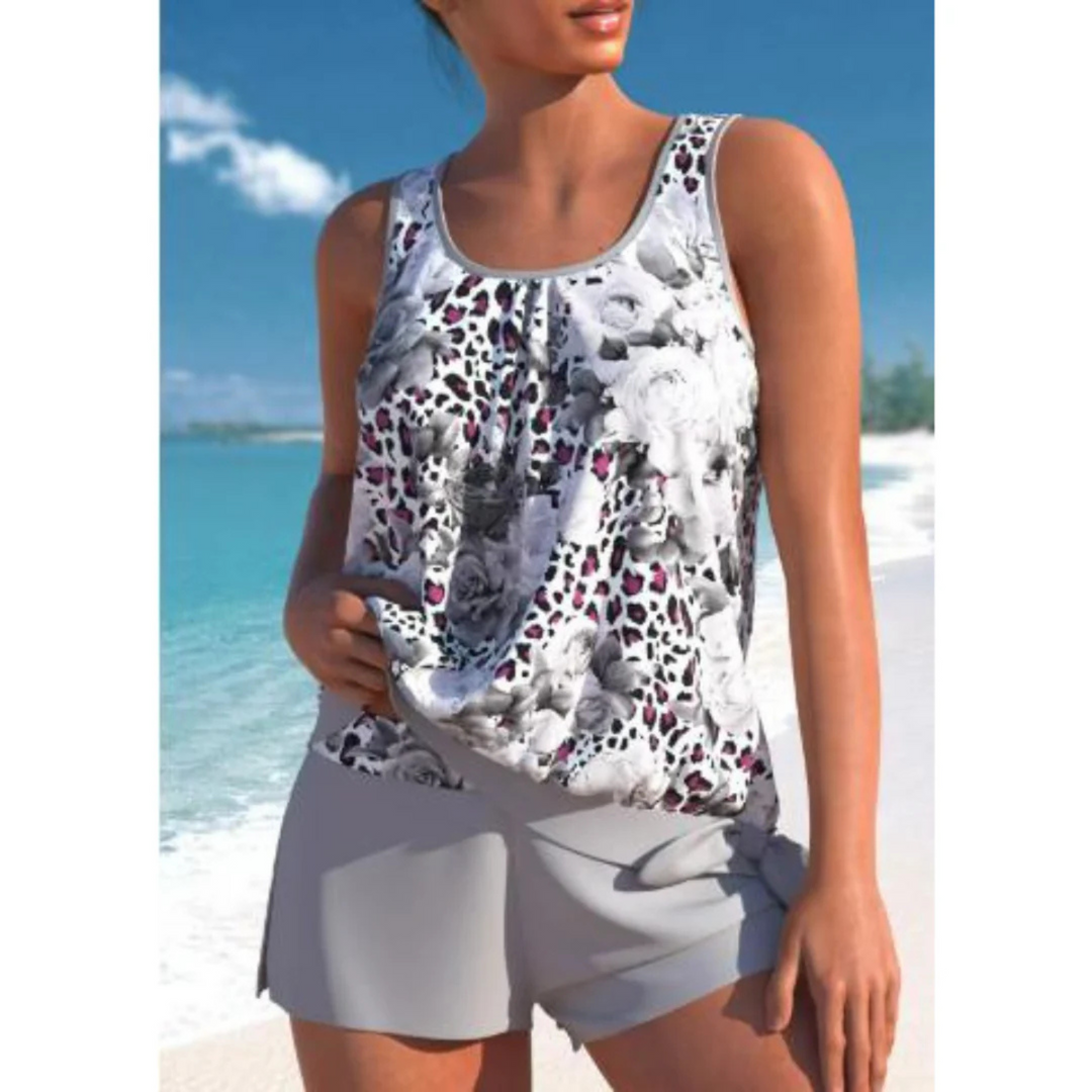Le tankini Angélique pour femme, au design tendance, avec un haut à imprimé floral noir et blanc, agrémenté de touches de fuchsia. Il est accompagné d'un short assorti, parfait pour une journée à la plage ou à la piscine, alliant confort et style.