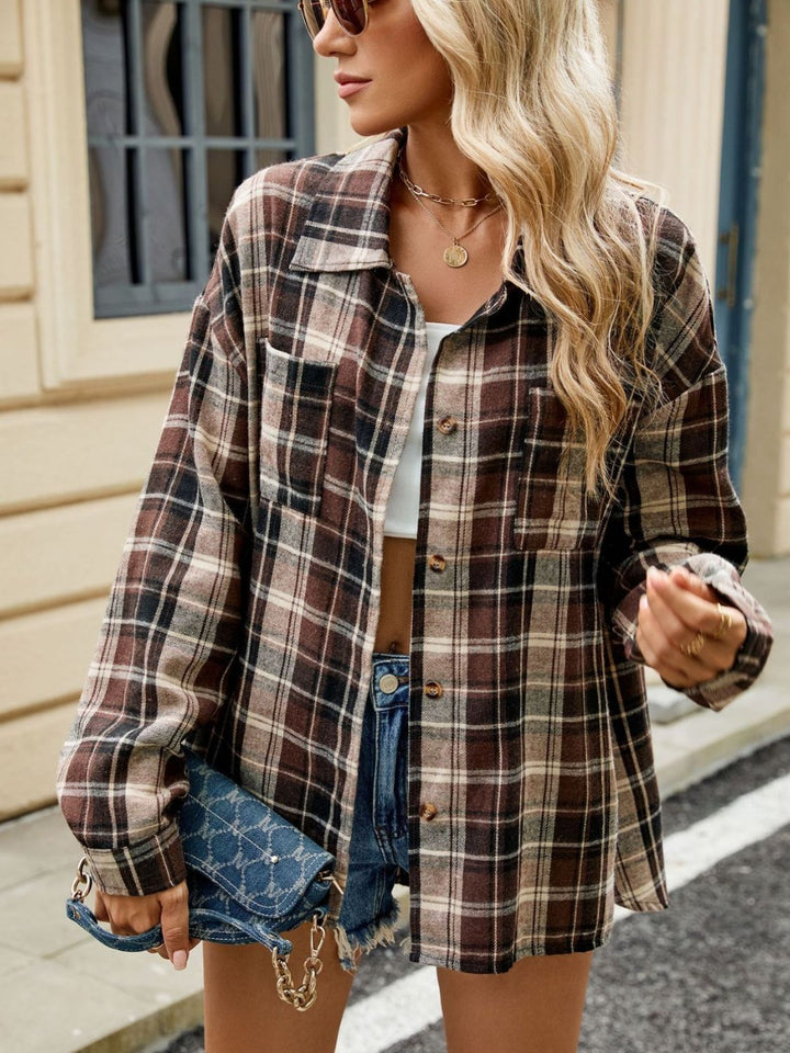 Femme portant une chemise longue à carreaux marron et crème avec des boutons, une coupe décontractée, un top blanc, des lunettes de soleil et un sac à main en chaîne, posant dans une rue urbaine.