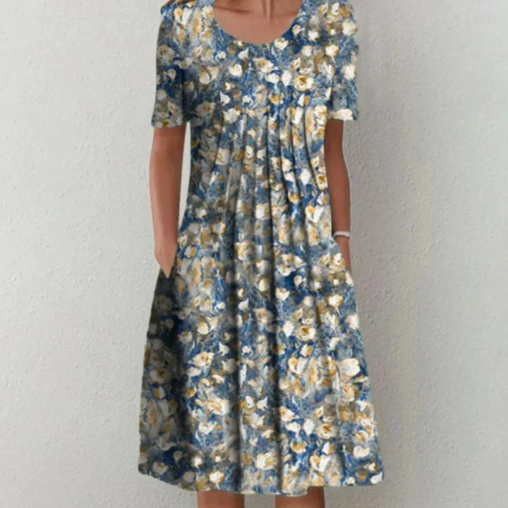 Robe estivale à motifs floraux bleu et jaune, avec une coupe fluide et féminine. Idéale pour un look élégant et confortable durant les journées chaudes, avec des poches pratiques sur les côtés.