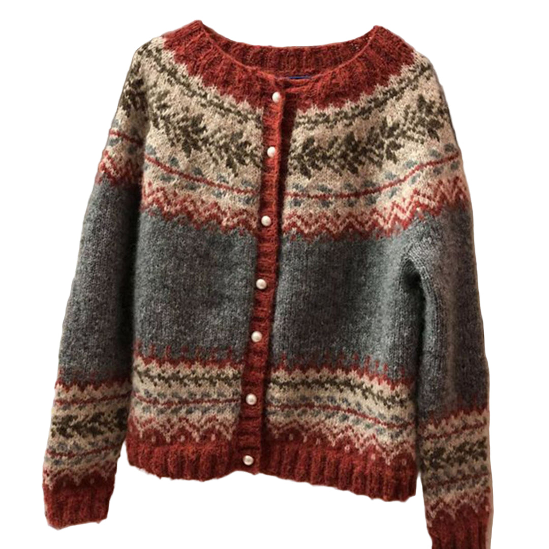 Cardigan en maille douce suspendu à un cintre, décoré de motifs nordiques dans des tons gris, rouge brique, beige et vert, avec une bande boutonnée ornée de petits boutons nacrés, photographié en intérieur.