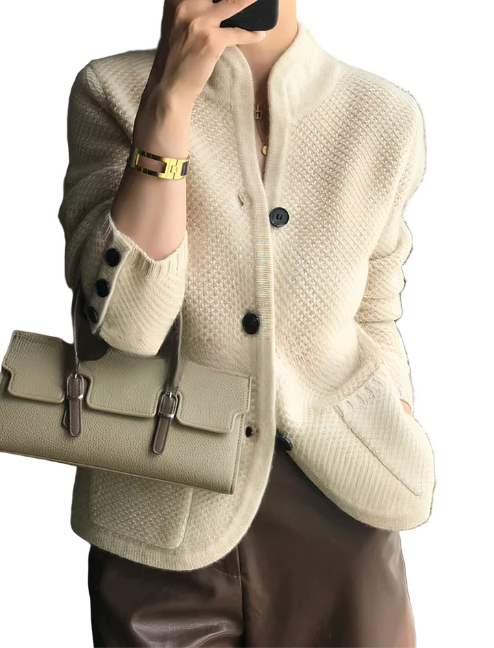 Femme portant un cardigan chic de couleur beige, doté d’une texture en maille raffinée, de boutons contrastés et de poches avant, assorti à un sac élégant et à un pantalon foncé pour un look moderne et sophistiqué.