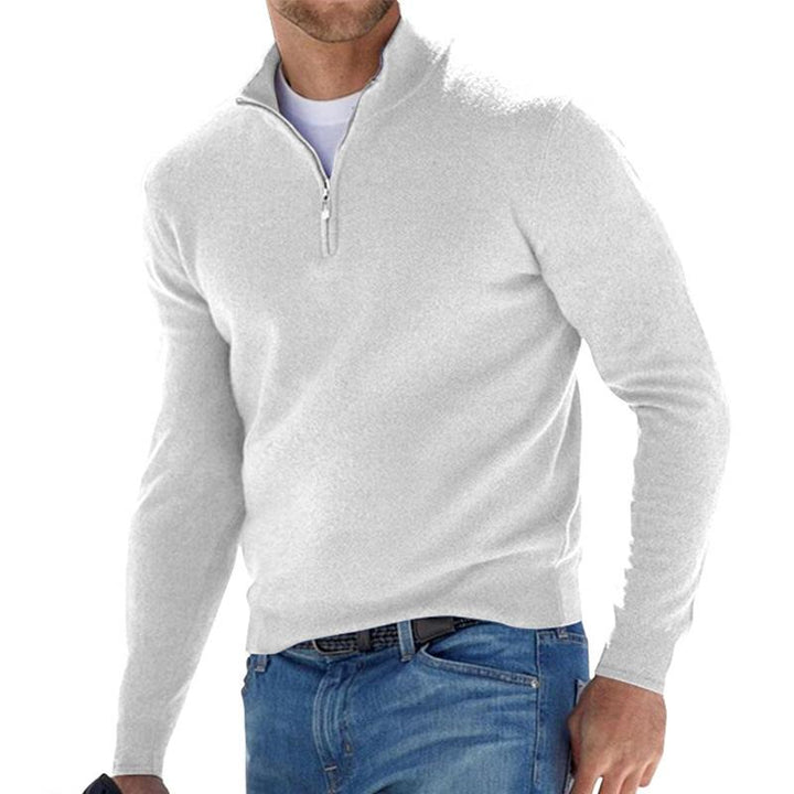 Pull pour homme blanc cassé avec col montant et fermeture zippée courte, coupe ajustée à manches longues, porté avec un jean bleu sur fond blanc.