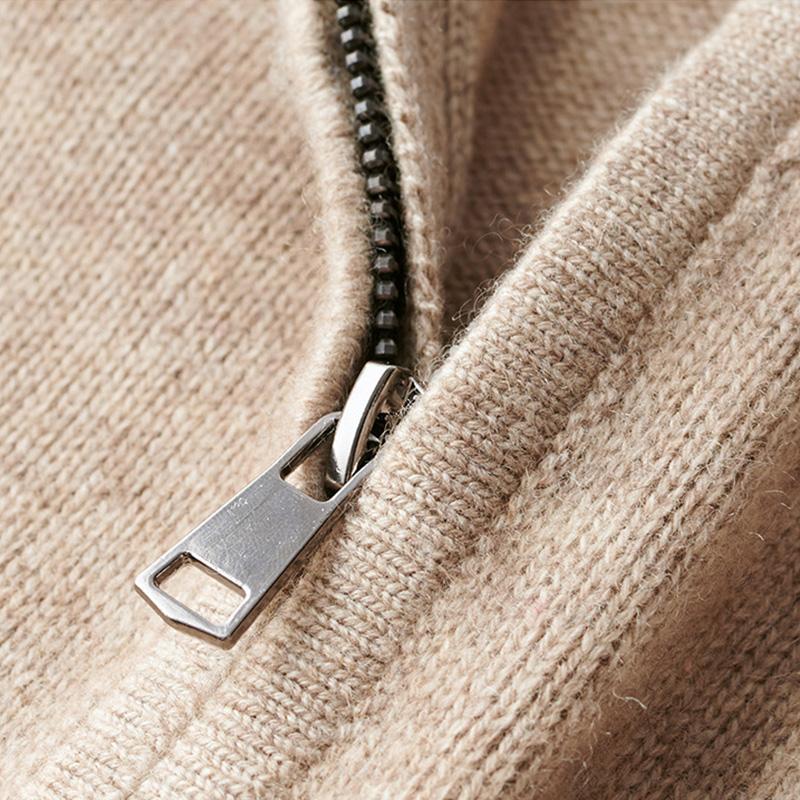 Gros plan sur la fermeture éclair métallique d’un pull en maille beige, montrant le col zippé et la finition tricotée.