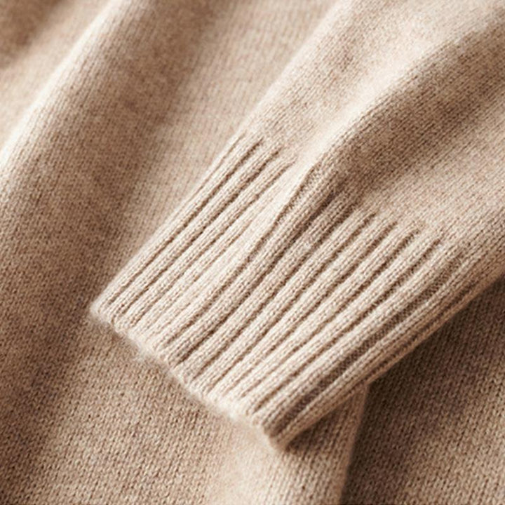 Détail d’un poignet côtelé sur un pull beige, montrant la finition tricotée et la texture douce de la matière.