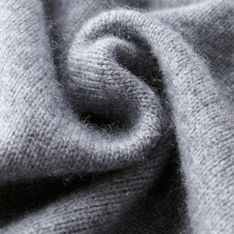 Gros plan sur un tissu tricoté gris doux et texturé, montrant la maille fine et l’aspect confortable de la matière.