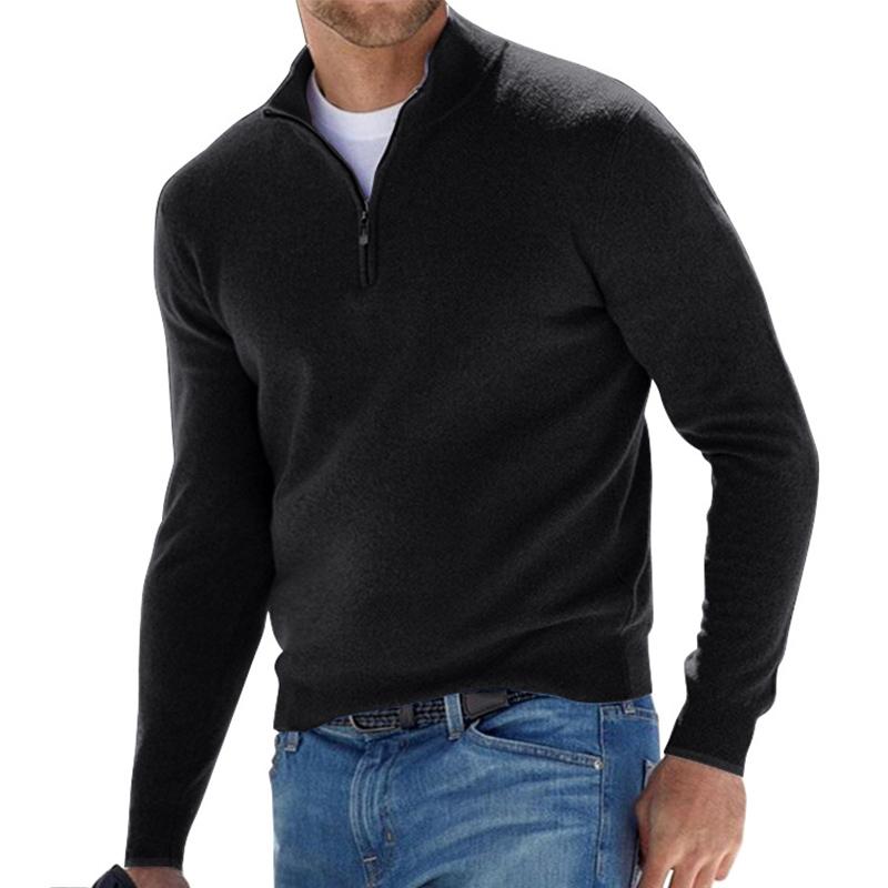 Pull pour homme noir avec col montant et fermeture zippée courte, coupe ajustée à manches longues, porté avec un jean bleu sur fond blanc.