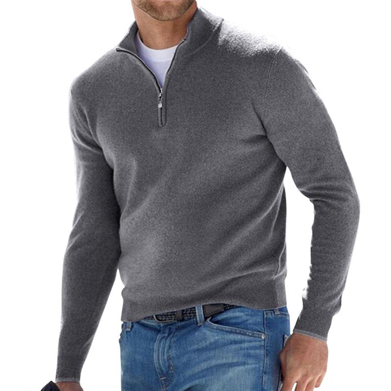 Pull pour homme gris anthracite avec col montant et fermeture zippée courte, coupe ajustée à manches longues, porté avec un jean bleu sur fond blanc.