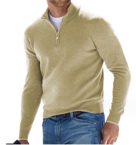 Pull pour homme vert olive clair avec col montant et fermeture zippée courte, coupe ajustée à manches longues, porté avec un jean bleu sur fond blanc.