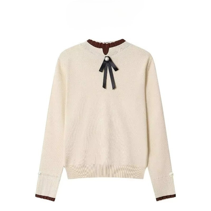 Pull Apricoat à manches longues pour femme, doté d'un col roulé côtelé marron contrastant. Le col est orné d'un ruban noir noué sous un bouton doré, pour une touche d'élégance. Les poignets sont agrémentés de petits boutons en nacre et d'un liseré marron, créant un style raffiné et féminin, idéal pour l'hiver.