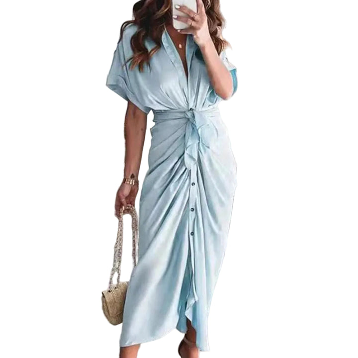 Robe midi bleu ciel avec une coupe fluide et une taille nouée, créant une silhouette élégante. Les boutons sur le devant ajoutent une touche moderne et raffinée, tandis que les accessoires dorés et le sac à main complètent le look chic, parfait pour des occasions décontractées ou formelles.