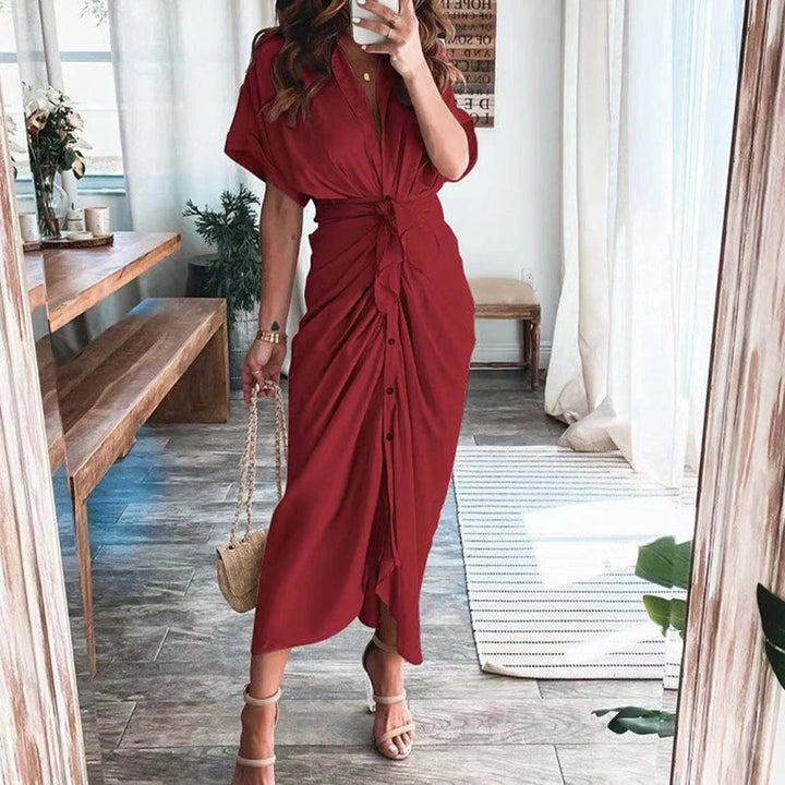 Robe midi rouge élégante avec une coupe fluide et une taille nouée, mettant en valeur la silhouette. Les boutons sur le devant apportent une touche chic et moderne, tandis que les sandales à talons et le sac à main complètent ce look sophistiqué, parfait pour les occasions spéciales.