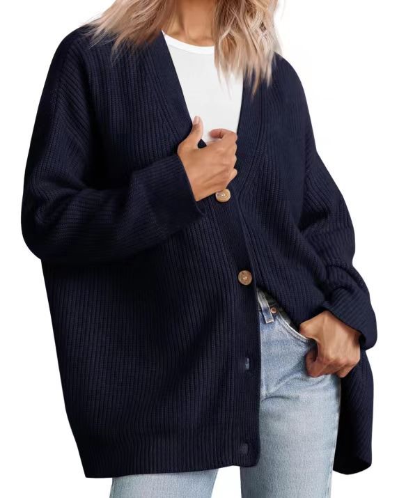 Femme portant un cardigan oversize bleu marine à col en V, fermé par de gros boutons, superposé à un t-shirt blanc et assorti à un jean clair.