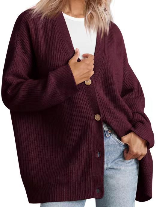 Femme portant un cardigan oversize rouge à col en V, fermé par de gros boutons, superposé à un t-shirt blanc et associé à un jean clair.