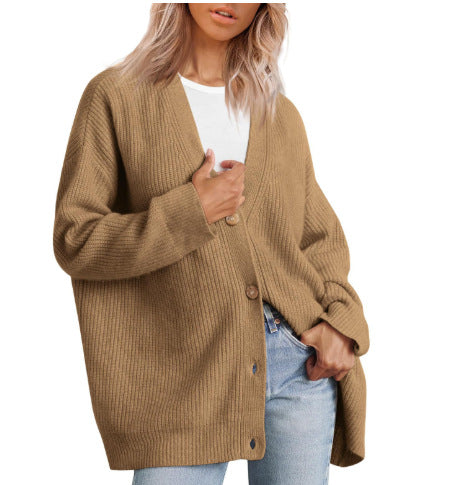 Femme portant un cardigan oversize beige à col en V, fermé par de gros boutons, superposé à un t-shirt blanc et associé à un jean clair.