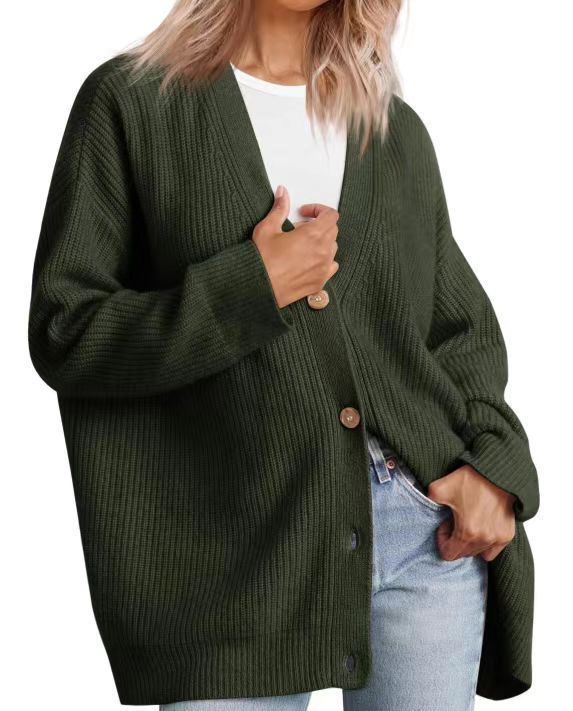 Femme portant un cardigan oversize vert foncé à col en V, fermé par de gros boutons, superposé à un t-shirt blanc et associé à un jean clair.