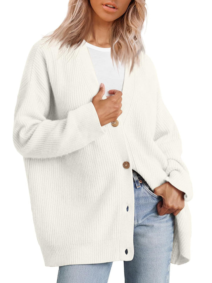 Femme portant un cardigan oversize blanc à col en V, fermé par de gros boutons, superposé à un t-shirt blanc et associé à un jean clair.
