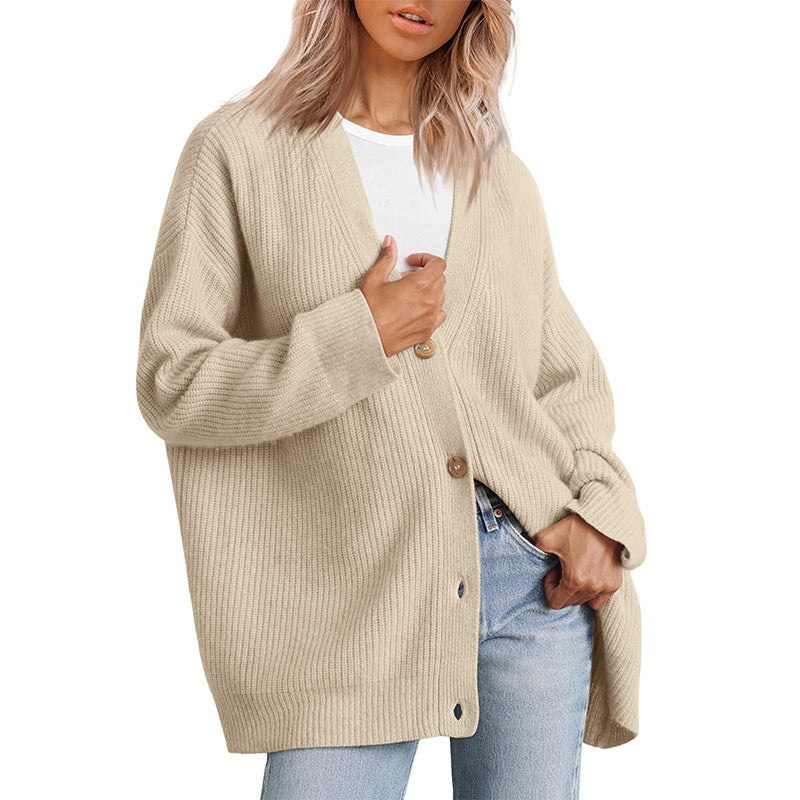 Femme portant un cardigan oversize beige sable à col en V, fermé par de gros boutons, superposé à un t-shirt blanc et associé à un jean clair.