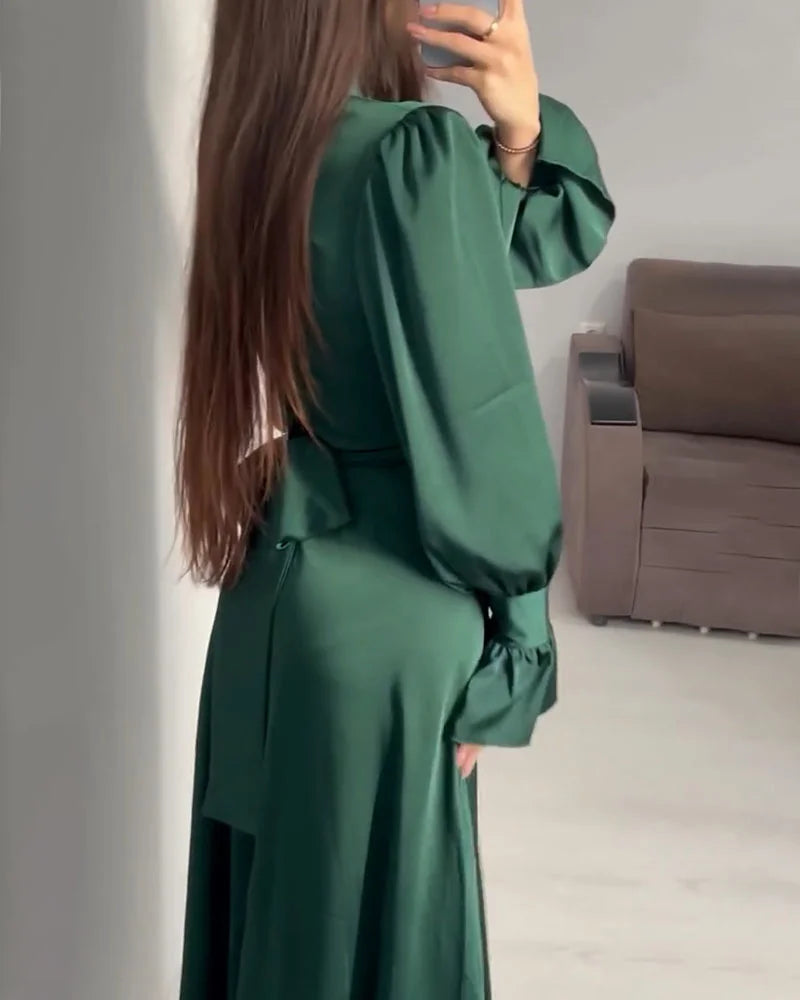 Vue de dos de la robe longue pour femme Aveline vert foncé, manches longues bouffantes et coupe fluide, portée en intérieur devant un canapé.