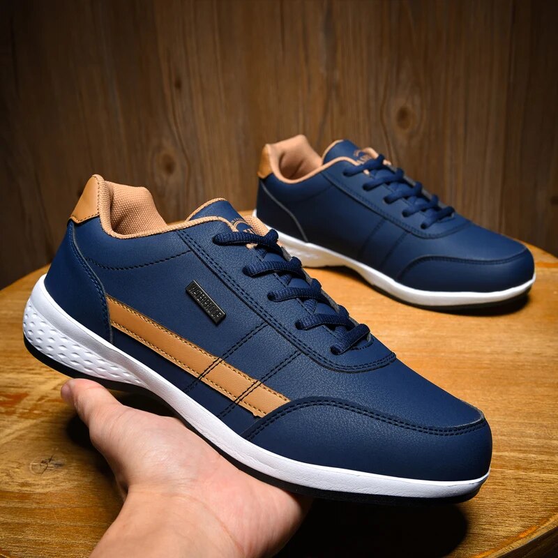 Paire de chaussures décontractées Benoît pour homme en bleu marine avec détails beige, lacets assortis et semelle blanche amortissante, présentées sur une table en bois, style moderne et confortable.