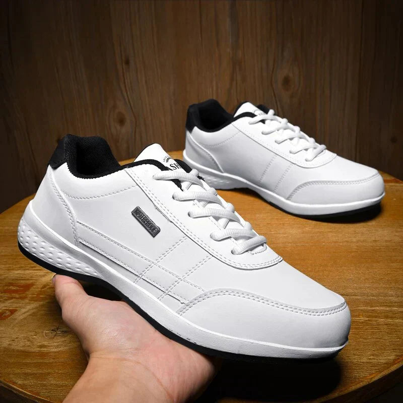 Paire de chaussures décontractées Benoît pour homme en blanc avec détails noirs, lacets blancs et semelle confortable, présentées sur une table en bois, design moderne idéal pour un look casual.