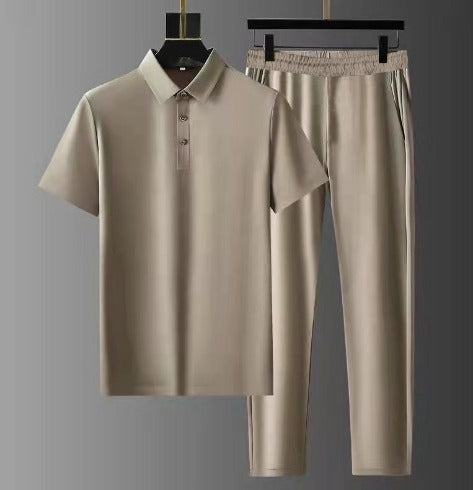 Ensemble d’été pour homme beige composé d’un polo à manches courtes et d’un pantalon léger, suspendu sur cintres sur fond gris.