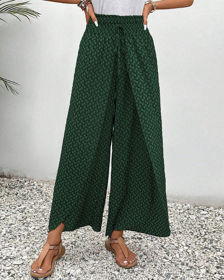 pantalon à coupe large avec taille élastiquée et motif géométrique vert, avec une fente sur le bas des jambes, parfait pour un look décontracté et moderne. À associer avec un top léger pour un style estival.