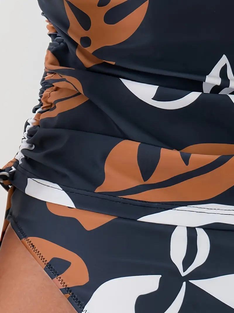 Détail du tissu à motifs tropicaux, mettant en valeur les fronces élégantes et la coupe ajustée du haut du tankini, pour un look à la fois confortable et stylé.