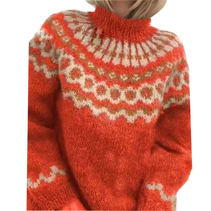 Femme portant un pull en maille épaisse de couleur orange vif, décoré de motifs nordiques en beige et blanc sur le haut du buste et les manches. Ce vêtement chaud au col montant offre une allure à la fois cosy et moderne, idéale pour la saison hivernale.