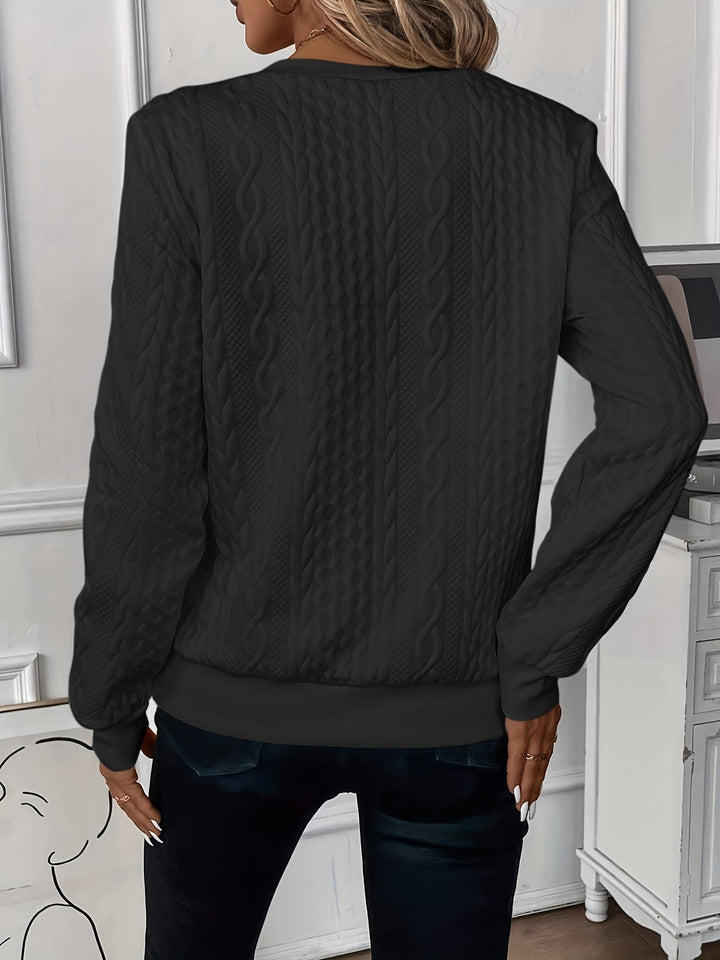 Vue arrière d’une femme portant un pull noir texturé à motifs torsadés verticaux. Le vêtement présente une coupe droite et des manches longues, avec des poignets côtelés pour un style élégant et moderne adapté à la saison froide.