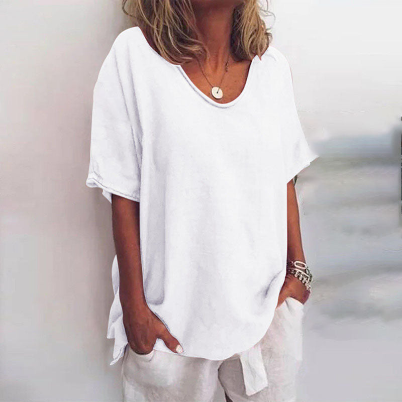 Blouse ample pour femme Cécile blanche unie, coupe décontractée à col rond et manches courtes, portée avec un pantalon clair et des bracelets.