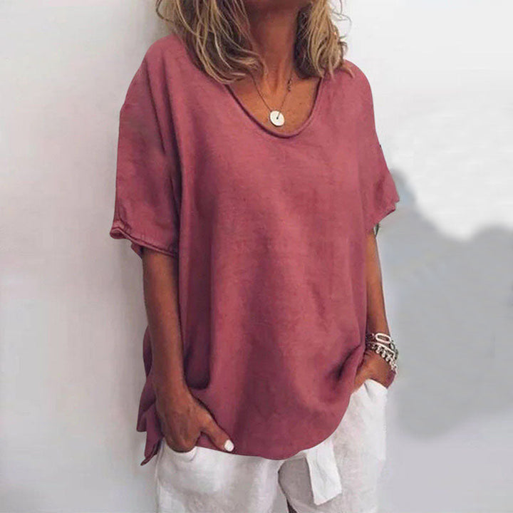 Blouse ample pour femme Cécile rose vieux uni, coupe décontractée à col rond et manches courtes, portée avec un pantalon clair et des bracelets.