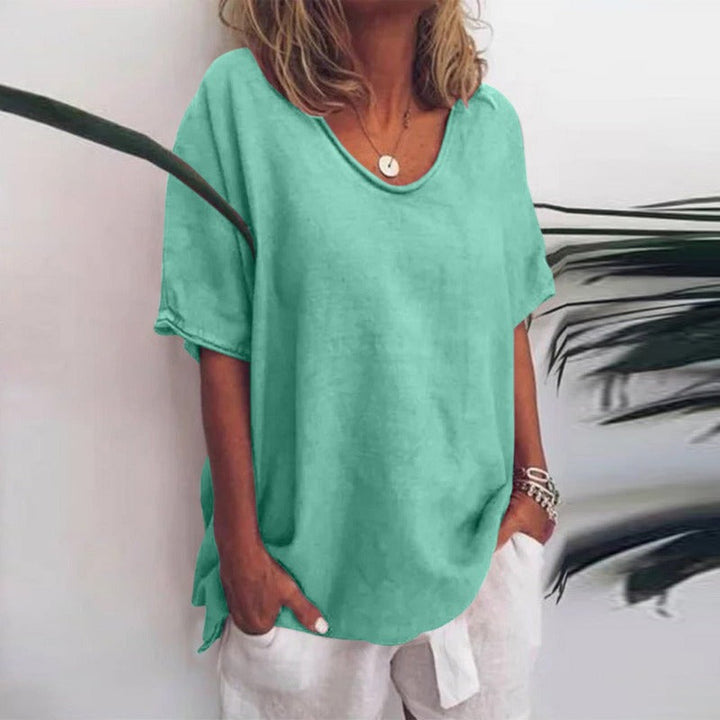 Blouse ample pour femme Cécile vert menthe unie, coupe décontractée à col rond et manches courtes, portée avec un pantalon blanc et des bracelets.